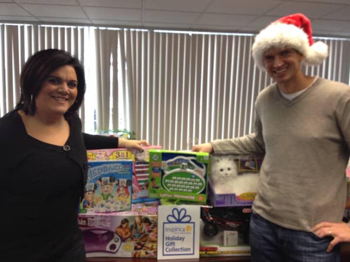 Rosa Torcasio, Human Resources administrator of 
CBP, and Chris Peck, chief executive officer of 
CBP, stand with the gifts their firm bought for children in need. 