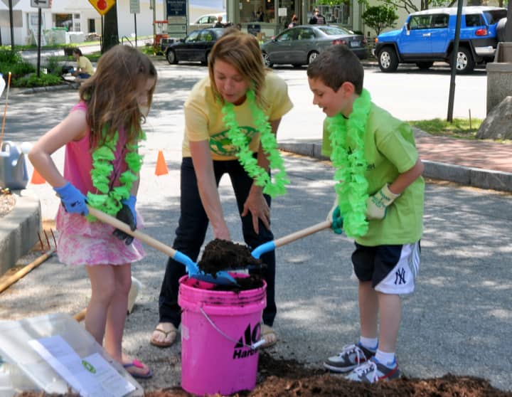 Terry Pike, co-chair of the Partnership&#x27;s Pound Ridge Pride Day, helps two youngsters do some planting in Scotts Corner.