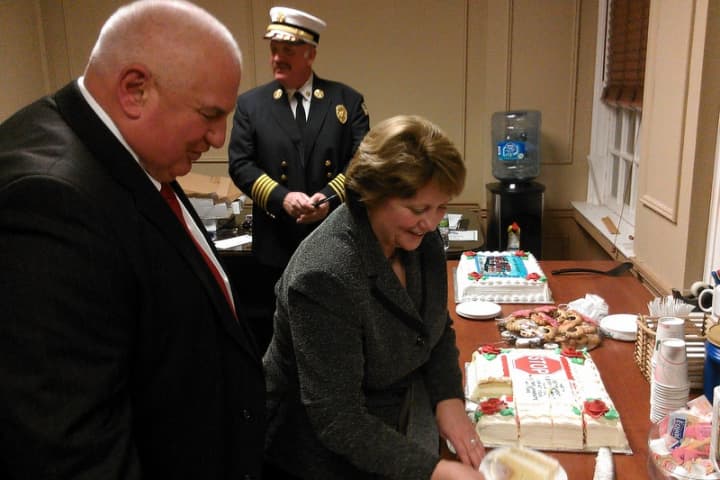 Mayor Mary Foster cuts cake for Police Chief Eugene Tumolo. left, and Lenny Varella, who will both be leaving their position in January.