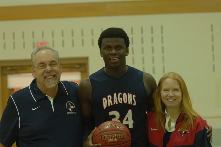 Greens Farms Academy basketball player Sean Obi, center, stands with his host parents from Greenwich, Steve and Bobbi Eggers after surpassing 1,000 career points.