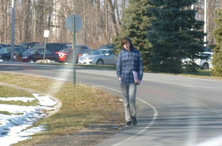 A Westchester Community College student walks into campus from Grasslands Road. The college&#x27;s student government is hoping the state will provide funding for sidewalks to increase student safety.