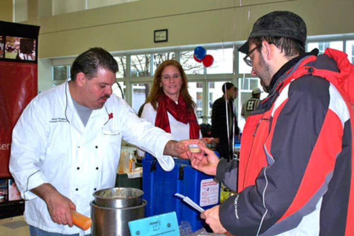 A participant at a past year&#x27;s Chowdafest receives a chowder sample from Southport Brewing Co.
