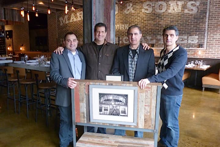 From left, Martin Racanelli, Nick Mautone, Alex Racanelli and John Racanelli stand behind a picture of the original Racanelli&#x27;s Pizza and Brew. The newly-renovated Greenburgh restaurant re-opened in December.