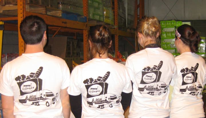 People working at a Move for Hunger food drive show off their shirts.