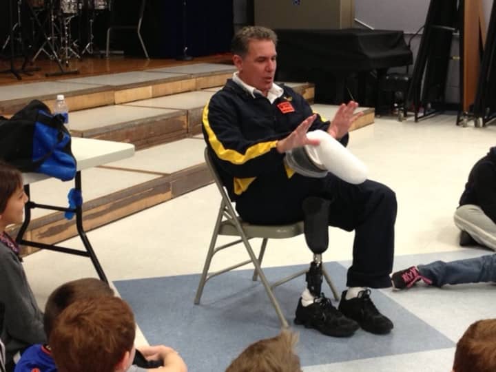 Dennis Oehler makes a moose with his hands and his amputated leg for fourth-graders.