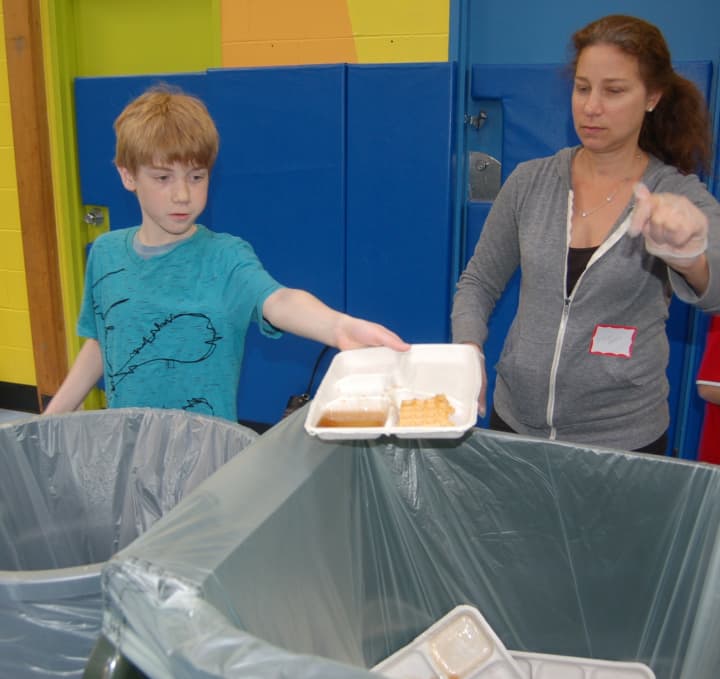 With guidance from parent volunteer Aimee Marcus, Wampus fifth-grader Sam Berglund tips his tray into the compostables bin.