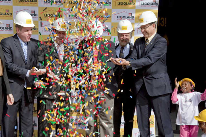 Lego bricks are dumped on company executives and local officials during a groundbreaking ceremony for Legoland Discovery Center Westchester last year. A city councilman is requesting the center change its name to include Yonkers. 