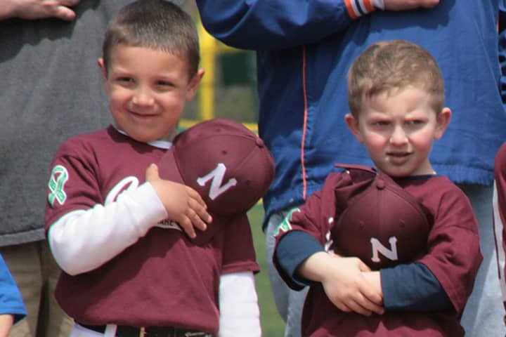 A couple of young ballplayers cover their hearts for the Pledge of Allegiance. 