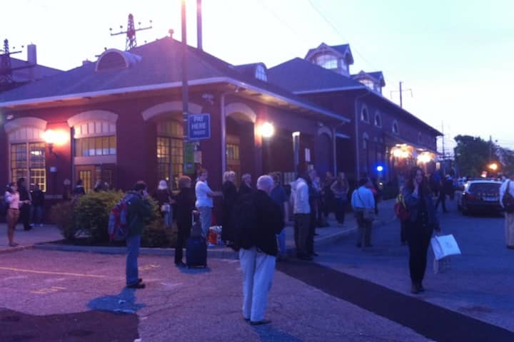 Stranded commuters crowd the parking lot at the South Norwalk train station after service was suspended.