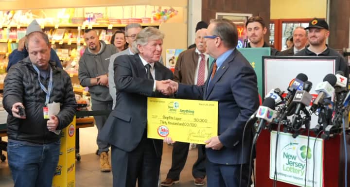 James Carey, executive director of the New Jersey Lottery, hands a $30,000 ceremonial check to&nbsp;Richard Saker, president and CEO of Saker ShopRites, at a news conference on Wednesday, Mar. 27.