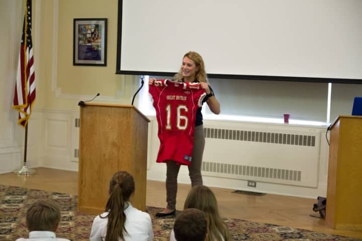 Phoebe Schecter shows her Great Britain football jersey to students at Ridgefield Academy. The former RA student is a linebacker for the Great Britain national team. 