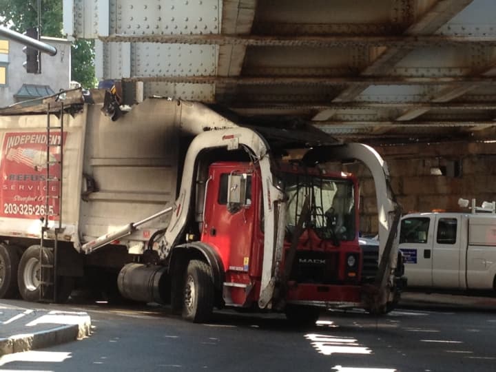 A garbage truck is stuck under the Washington Street train bridge in Norwalk on Monday.