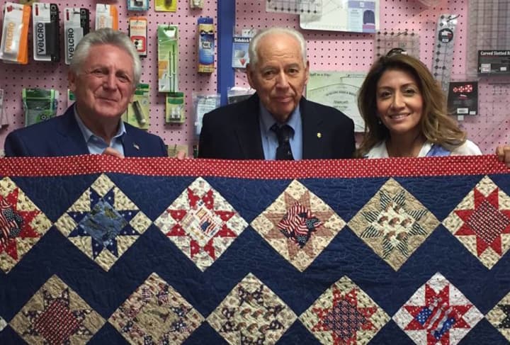 Norwalk Mayor Harry Rilling, left, and his wife, Lucia, right, present a quilt at Christie&#x27;s Quilting Boutique in Norwalk on Saturday.
