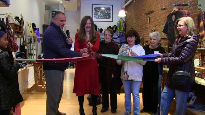 Jeorjia Shea, center, in red, cuts the ribbon at the official opening of her artisan boutique, Quirkshop, in Peekskil. At left is Peekskill Mayor Frank Catalina.
