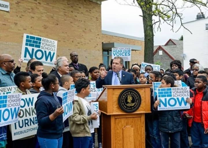 Yonkers Mayor Mike Spano, at podium, speaks at a rally for a schools rebuilding project in front of the Martin Luther King Jr. Academy Wednesday morning.