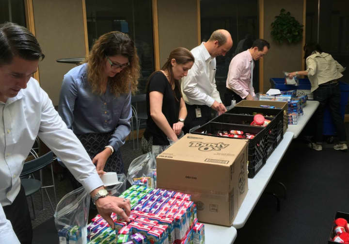 The Center for Food Action anticipates having to step up its community donation efforts. Here the Stryker Hip Development Team assembles 500 snack packs.