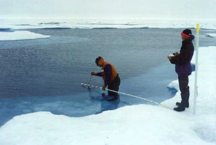 Researchers collect data in a melted ice pack of the Arctic Ocean while studying Arctic melt and other aspects of climate change.