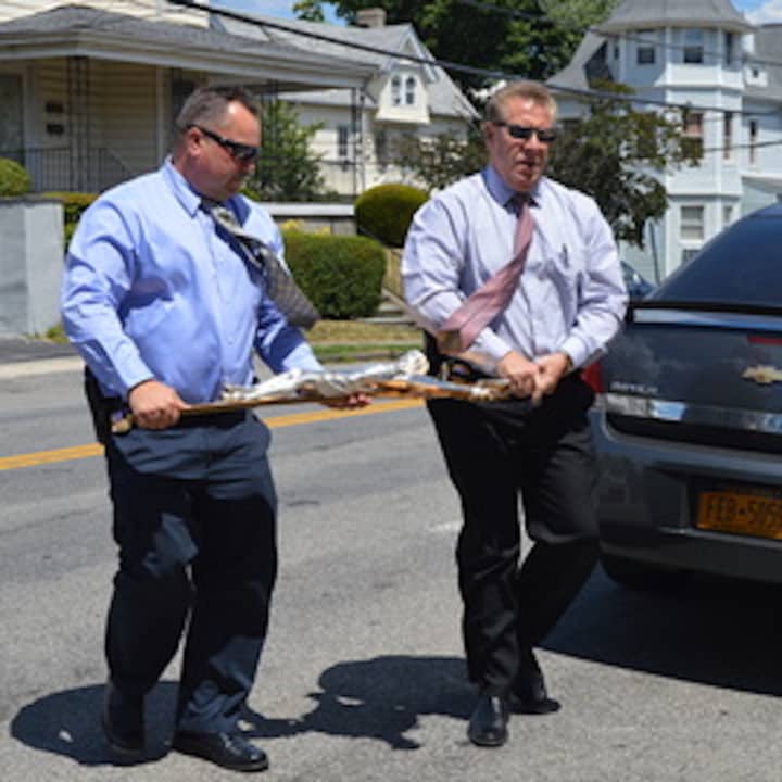 Yonkers Police Detectives Stephen Sokolik and Stephen Kerner carry the crucifix as they return it to the church.