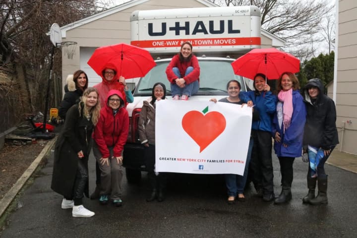 Amber Lewis, the founder of Greater NYC Families for Syria, sits on top of the U-Haul truck at their first-ever donation event in Eastchester surrounded by other volunteers.