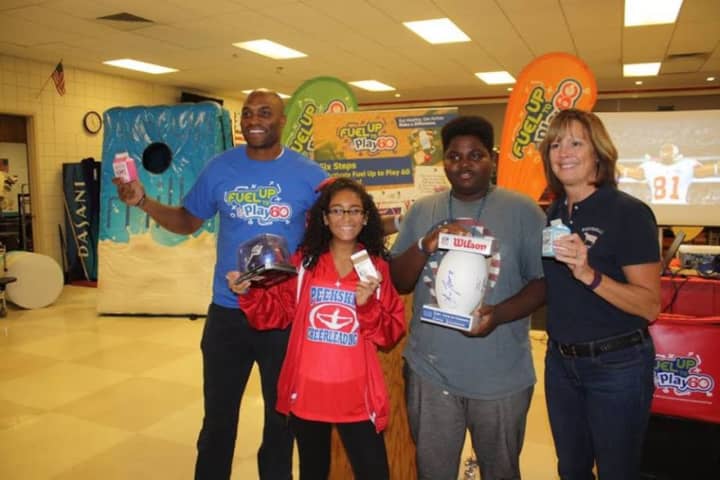 Former Giants wide receiver Amani Toomer and Lisa Porter of Porterdale Dairy Farm stand with two Peekskill City School District students.