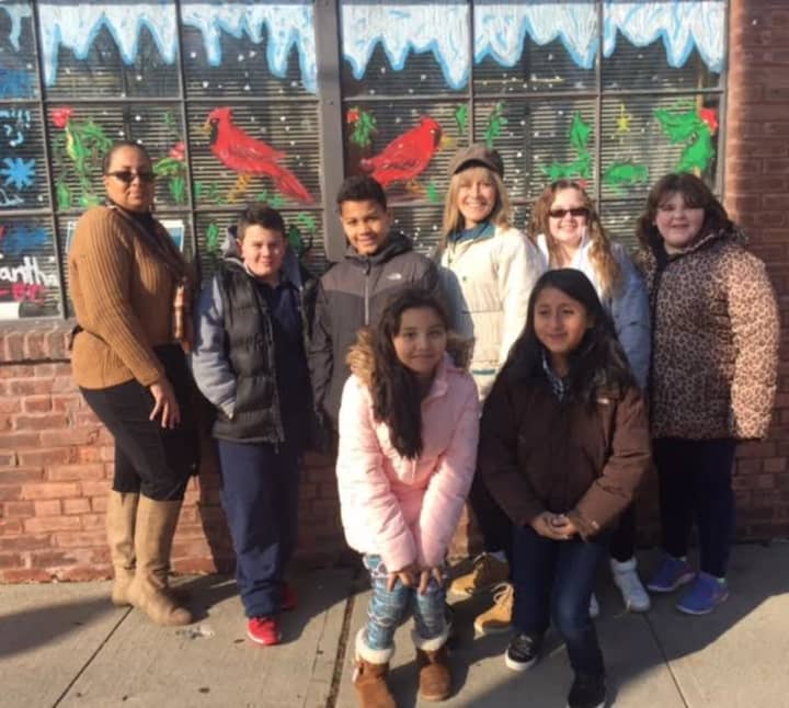 Postmaster Penny Jackson (Far Left) and Buchanan - Verplanck Elementary School Art Teacher Kathy Irwin (Back Row - 3rd from right) admire the fourth and fifth grades student’s holiday artwork on the Post Office front window.