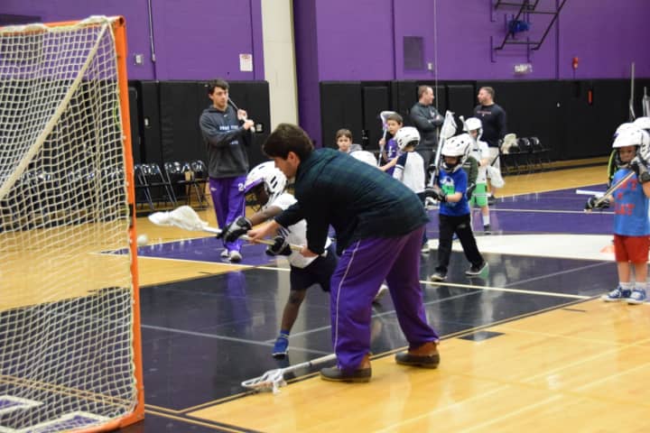 John Jay varsity lacrosse player Jack Gorman shows proper shooting technique to a recruit at John Jay Youth Lacrosse’s new player clinic in Cross River on Saturday, Jan. 21.