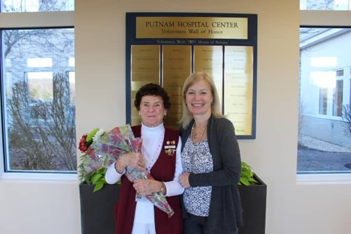 Volunteer Terry Scrivani gets her name on a plaque and accepts flowers from Michelle Piazza, director of volunteer and pastoral services at Putnam Hospital Center, for 7,500 hours of service.