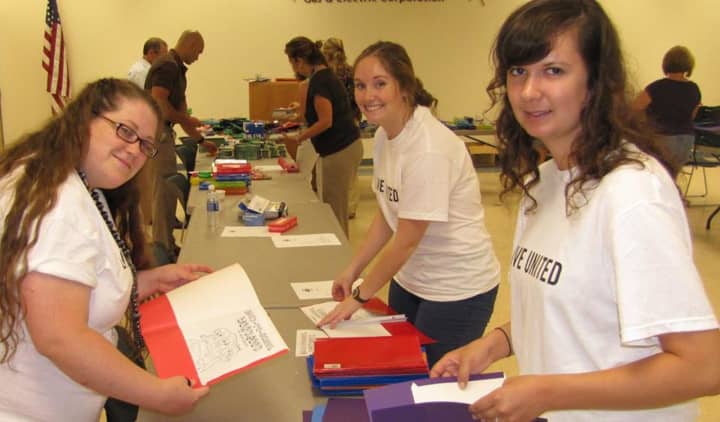 Volunteers stuff folders and backpacks during a prior United Way school-supplies event.