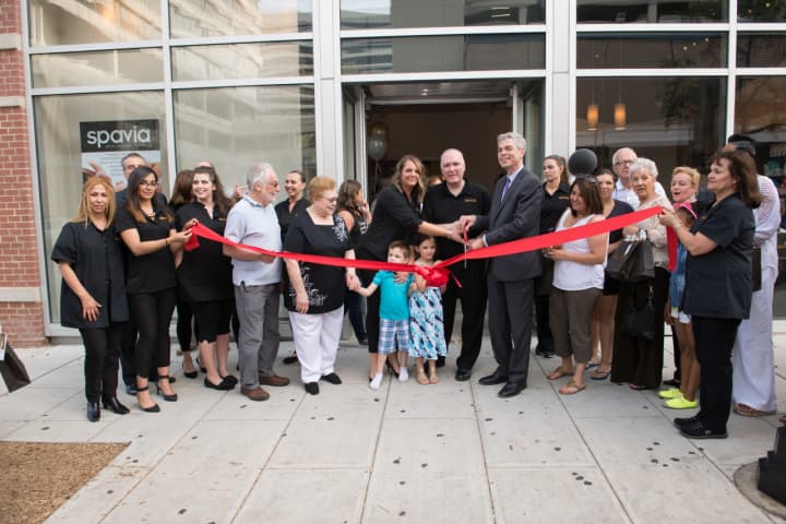 White Plains Mayor Tom Roach assists spavia owners Mike and Maria Hourigan with the ribbon cutting ceremony for the new spa location in White Plains on Main Street.