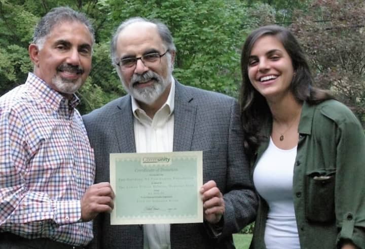 Dennis Tarzian, left, of Fund for Armenian Relief, accepts the donation from Barry Halejian and Sarah Halejian.