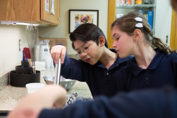 Students peer into a bowl as they make yogurt during a Nutrition Week activity Tuesday at Ridgefield Academy. 