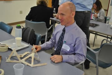 Putnam Valley math teacher Joe Mahoney attempts to build a structure from Popsicle sticks and tape that can support 12 pounds.
