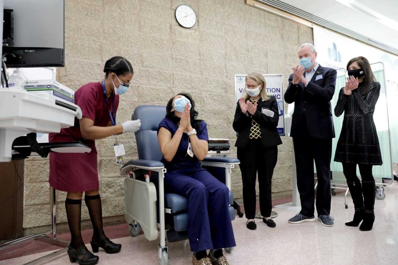 Maritza Benitez clasps her hands in prayer as she becomes the first New Jersey healthcare worker to get the COVID-19 vaccine Tuesday.