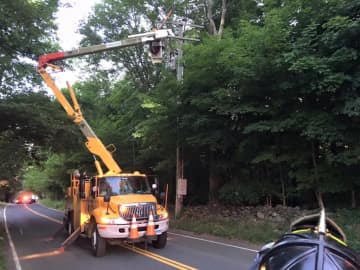 The Monroe Volunteer Fire Department helps on Fan Hill Road near East Maiden Lane as Eversource repairs a power outage early Saturday.