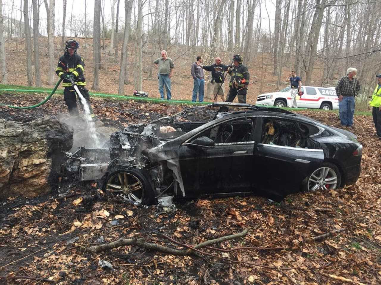 Firefighters work to douse flames from a car fire.