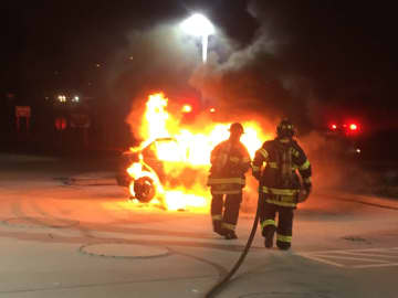 Fairfield firefighters extinguish a burning car about 50 feet from the gas pumps at the Cumberland Farms at 975 Kings Highway E. on Sunday morning.
