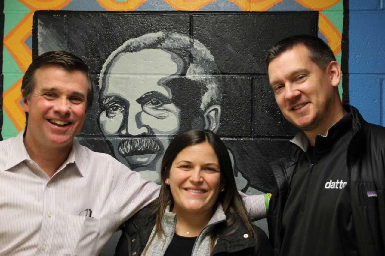 Joe Gallagher, Carver, Director of Philanthropy; Kate Scully, Datto Event Planner; Nicholas Hagen, Sales Manager-Midwest. Image taken at Carver Community Center; drawing of Carver’s namesake, George Washington Carver on wall in background.