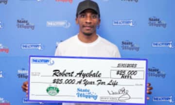 Robert Ayebale holding his winning prize from the Massachusetts State Lottery
