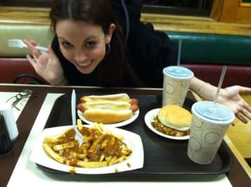 A patron at The Hot Grill in Clifton pauses for a photo opt before chowing down on its Texas hot wieners and fries drenched in gravy.