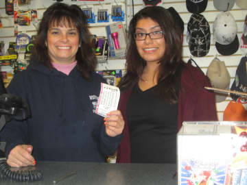 Employees at Westchester Tobacco and Stationary hold up a Powerball ticket.