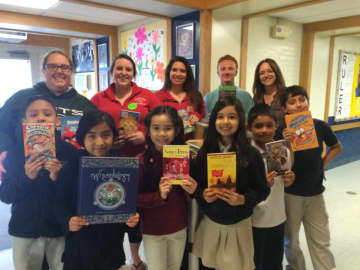 Madison School third-graders in Bridgeport hold up the free books they'll take home, thanks to a book drive at Sacred Heart University of Fairfield.