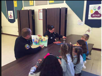 Bethel Police Officer Robinson and School Resource Officer Courtney Whaley read to children on story time night at Berry Elementary School in Bethel.