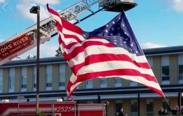 Members of Toms River Fire Department No. 1 hoist an American flag outside Community Medical Center.