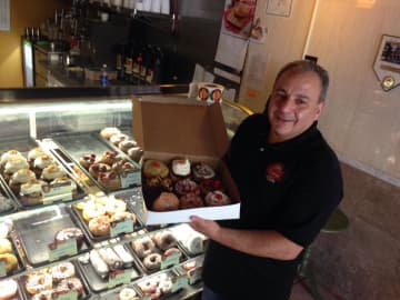 Jule Hazou displays his freshly-made doughnuts in the New Milford store.