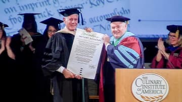 <p>CIA President Tim Ryan presenting Anthony Bourdain with an honorary doctorate from The Culinary Institute of America.</p>