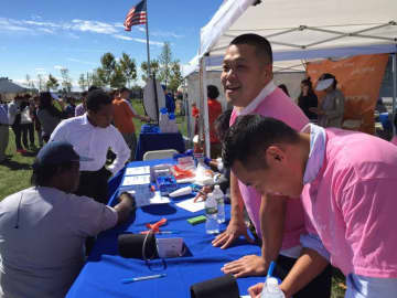 Dong Joo Lee, left, volunteers at the Holy Name Medical Center tent for his bachelor party.