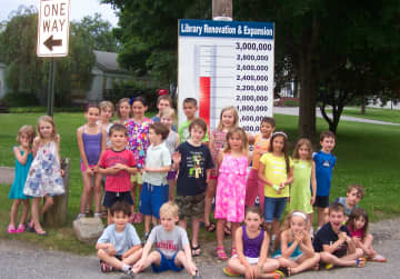 Children attending the Lewisboro Librarys Summer Reading Kick-off Treasure Hunt pose by the Building Campaigns Fund-raising Thermometer.
