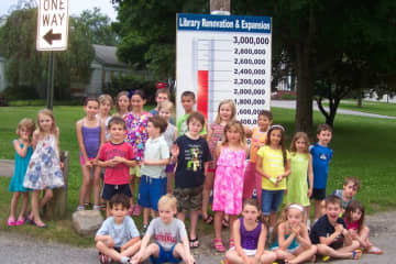 Children attending the Lewisboro Librarys Summer Reading Kick-off Treasure Hunt pose by the Building Campaigns Fund-raising Thermometer