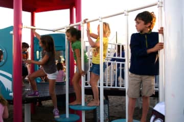 Children play on the new playground built in memory of Jessica Rekos on Fairfield's Penfield Beach after its grand opening Saturday.