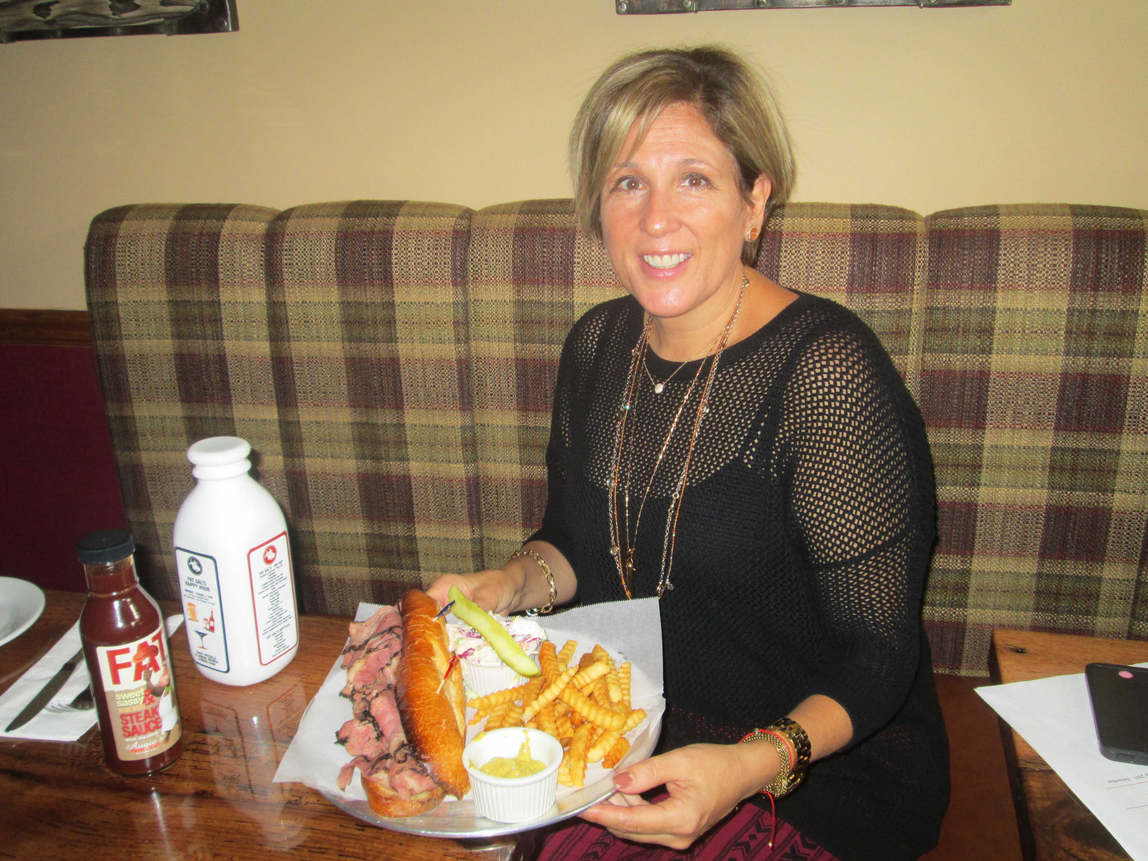 Audrey Hochroth in front of a pastrami sandwich, one of the delicacies offered at Fat Sal's.